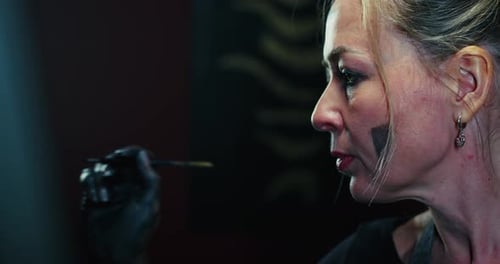 Femme peignant avec un pinceau dans une pièce sombre