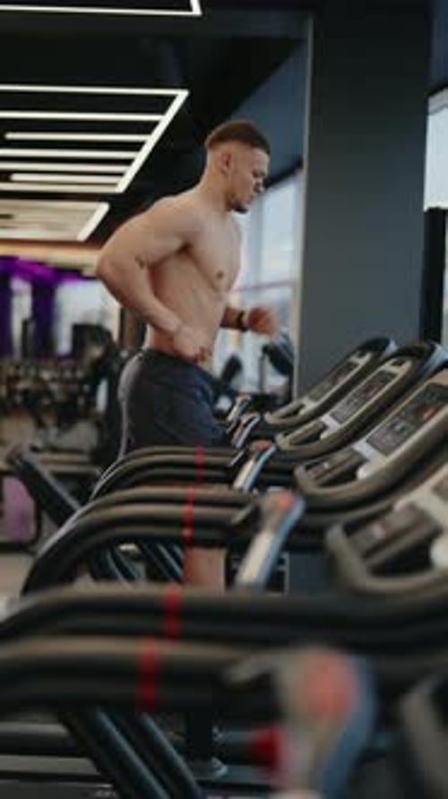 Muscular Man Running on Treadmill in Modern Gym