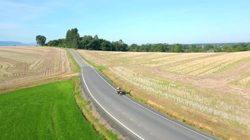 Aerial Of Vintage Motorcycle Riding a Country Road Throught Fields In Summer