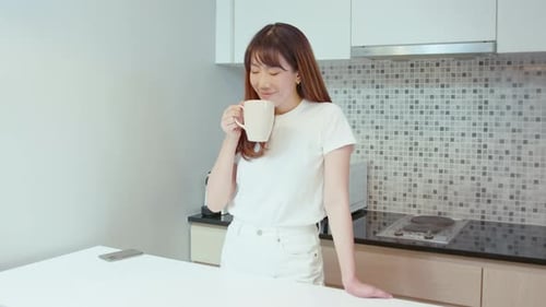 Woman Enjoying Drink in Bright Modern Kitchen