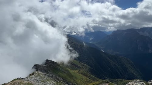 Massive White Clouds Rolling Over Majestic High Altitude Mountain Peaks