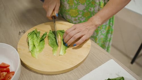 Woman Chopping Romaine Lettuce on Round Wooden Board in Kitchen, Close Up of Hands and Fresh Greens,
