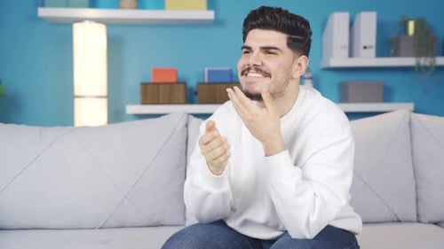 Smiling Man Uses Mobile Phone on Couch Indoors