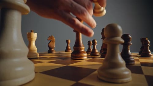 Hand Moves Chess Pawn in Dramatic Lighting