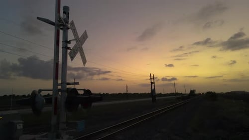 Aerial Shot Passing Railroad Crossing Sign Silhouetted Against Multi-Colored Sunset In Texas, U.S.A.