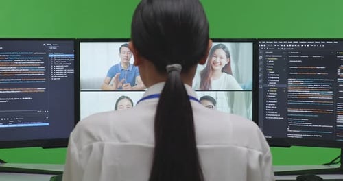 Entwicklerin hat Video, während sie Code mit mehreren Computerbildschirmen im Green Screen Studio schreibt