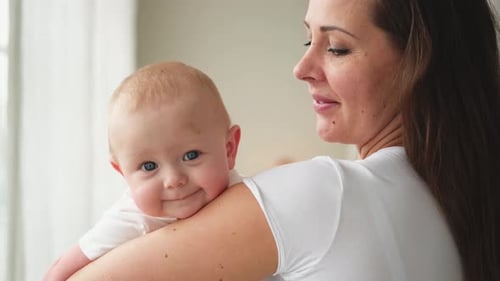 Loving Mother Holds Smiling Infant in Bright Room