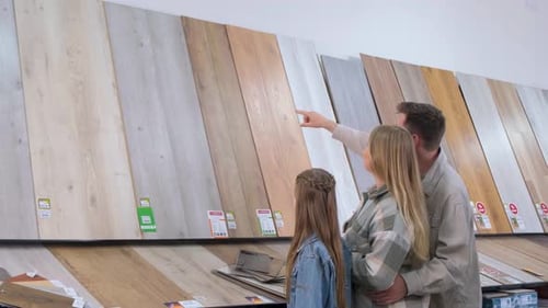 A Young Family in a Hardware Store Chooses a Wooden Laminate Surface for Home Renovation