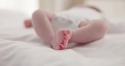 Sleeping Infant's Tiny Feet Relaxed on White Sheet