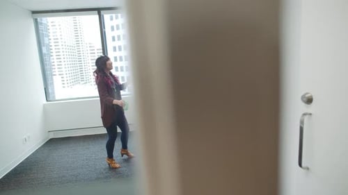 Businesswomen With Tape Measure Measuring Wall In New Office
