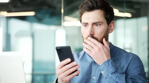 Worried Man Looking at Phone in Modern Office