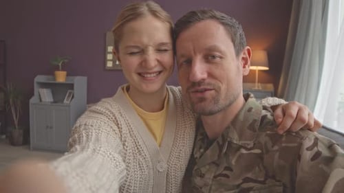 Girl and Soldier Smiling at Camera Indoors