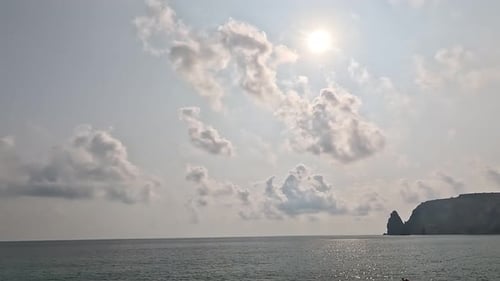 Cumulus duveteux en timelapse se déplaçant dans un ciel de coucher de soleil éclatant au-dessus d'une mer calme, nature aérienne abstraite