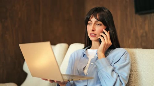 Woman using laptop and talking on phone