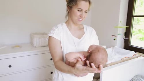 Woman Tenderly Holding Newborn Infant in Nursery