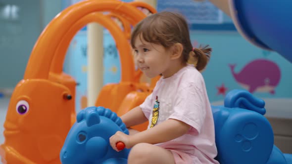 Child playing on rocking horse in a colorful indoor play area, slow ...