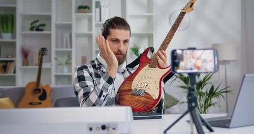Man Demonstrates Electric Guitar While Recording Video