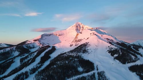 A drone shot of snowy Big Sky, Montana in winter, showcasing the ski resort and majestic mountain te