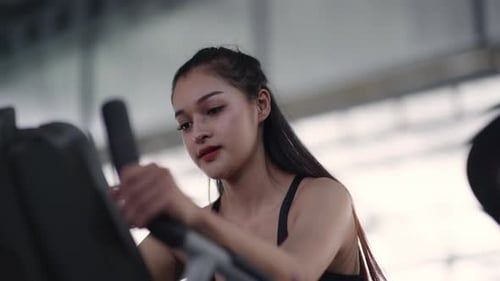 Sport woman is exercising and biking on Stationary Bike in gym.