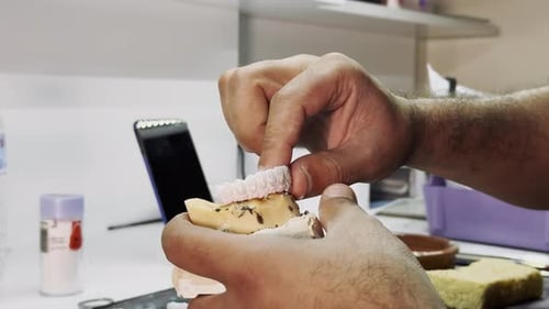 Dental Craftsman Fitting Temporary Crown onto a Model