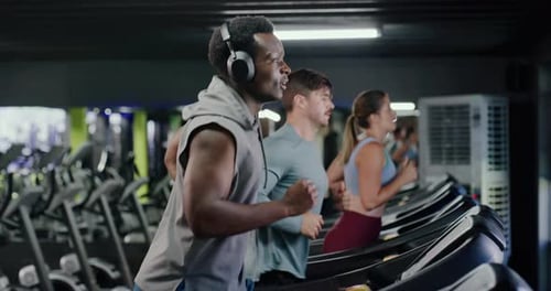 Headphones, training and man on treadmill in gym for running, workout or fitness with health