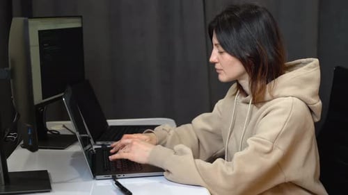 Woman Typing on Laptop at Desk in Office