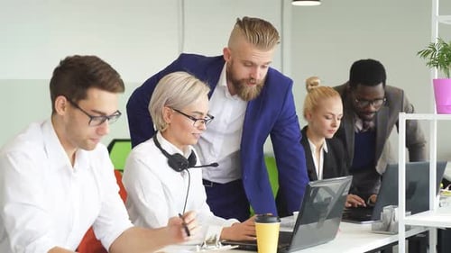 Friendly Team of Colleagues Works in the Office People in Formal Clothes Sit at the Table and Use