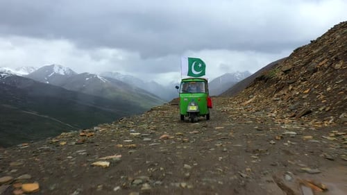 Prise de vue par Drone d'un tuk-tuk sur le col de Babusar au Pakistan, avec quelques véhicules sur la route en contrebas dans le Ka