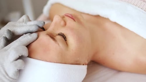 Woman Receiving Relaxing Facial Treatment in Bright Spa