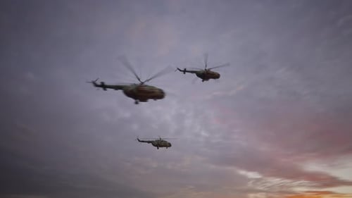Military Helicopters Flying Formation in Cloudy Sunset Sky