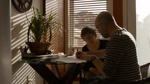 Elderly Mother Filling Out Questionnaire With Help From Caregiver Adult Son At Home Wide Shot 24fps