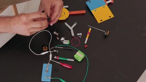 Person Assembling Educational Robotics Kit on a Table