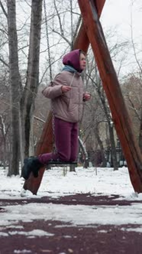 Winter Swinging in Snowy Park with People Running in Distance