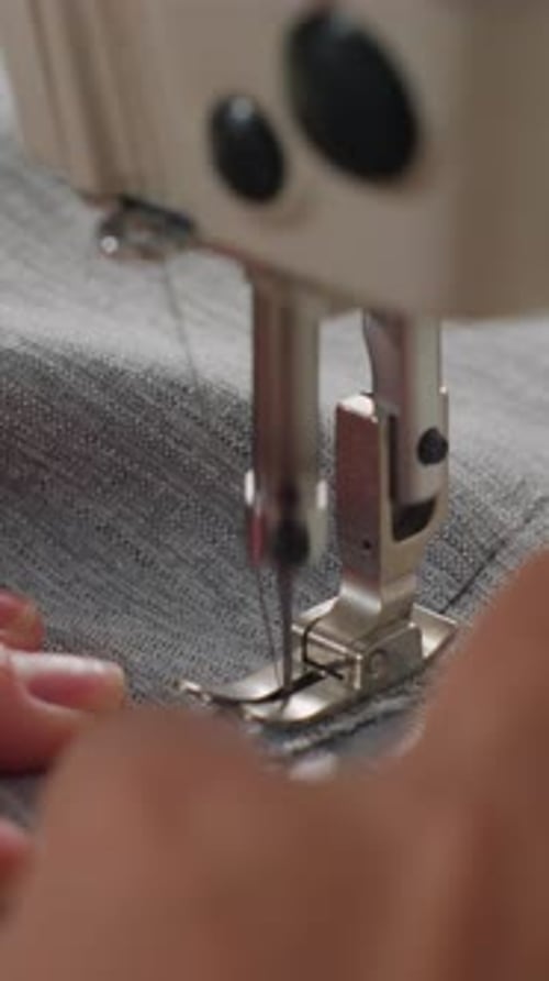 Close up sewing machine stitching gray fabric material