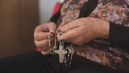 close up on Hands of an old woman snatching the rosary while praying