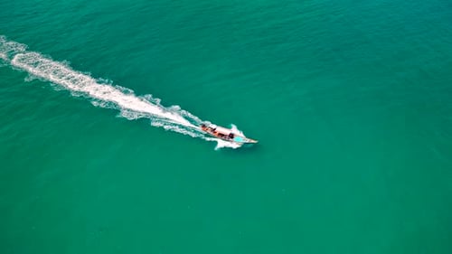Drone shot of a small boat sailing next to the island.
