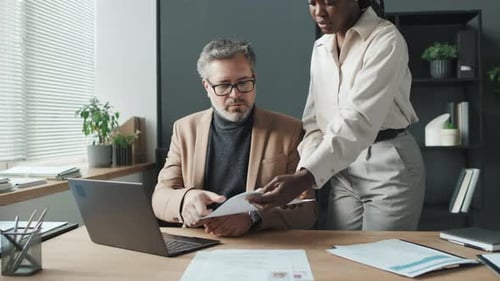 Caucasian Businessman Typing On Laptop, Black Colleague Bringing Him CVs