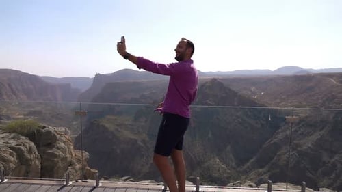 Cheerful man takes selfie with breathtaking canyon view from hotel terrace