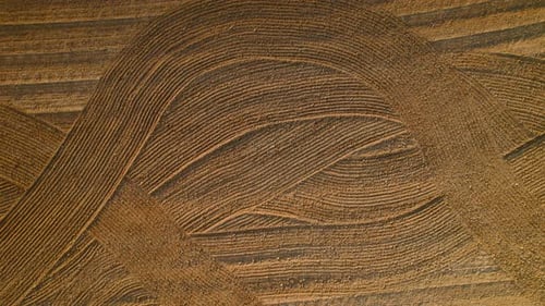 Detailed aerial view of patterned soil, where lines and textures indicate agricultural plowing in a