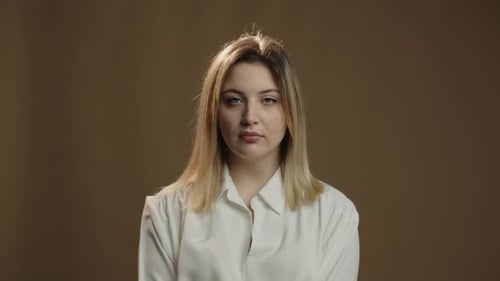 Pensive Blonde Woman Looks to Camera and Begin to Smile Front View of Attractive Girl in White Shirt