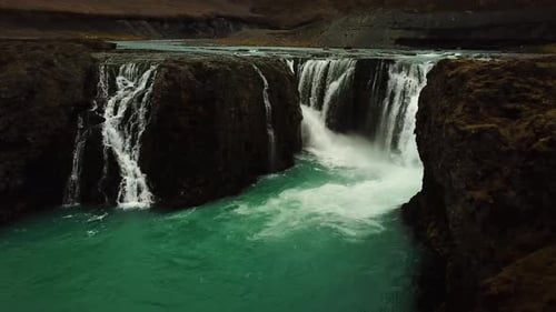 Aerial drone view of a river flowing down a large waterfall, in Iceland