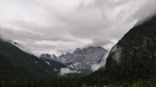 Drone aerial view of clouds drifting over the majestic peaks of the Alps mountains