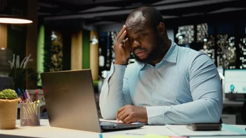 Black Troubled Worker Rubbing His Head in Frustration and Weariness