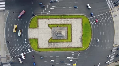 Drone topdown timelapse video of a round about. Cars and buses drive around the center plaza. Drone