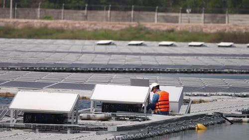 Schwimmendes Solarpanel auf dem Teich. Der Arbeiter wartet und überprüft schwimmende Photovoltaikmodule.