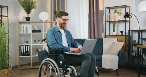 Man in Wheelchair Working at Laptop at Home