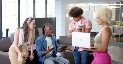 Discussing project, diverse team collaborating in office using tablet, smartphone, and laptop
