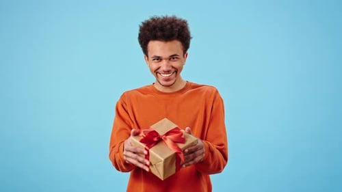Smiling Man Offering Gift on Blue Background