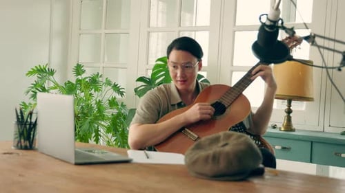 Young Adult Plays Guitar in Home Studio
