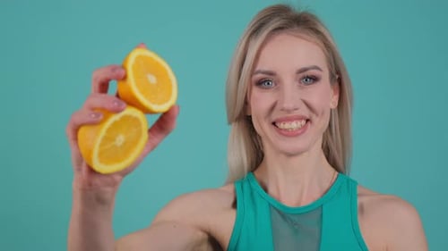 Smiling Woman Holding Orange Halves Close Up